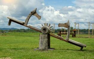 une bascule est une champ joueur fabriqué de bois, assemblé avec une longue étroit planche mis à travers le faisceau. à le fin de le arbre est une endroit à s'asseoir. avoir le les enfants balançoire en haut et vers le bas alterner côtés. photo