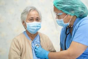 médecin utilisant un stéthoscope pour vérifier une patiente asiatique âgée ou âgée portant un masque facial à l'hôpital pour protéger l'infection du coronavirus covid-19.