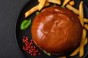 Burger avec juteux du boeuf escalope, fromage, tomates, sel, épices et herbes photo