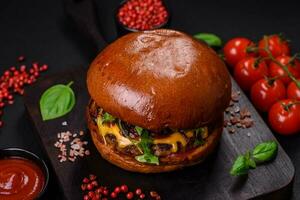 Burger avec juteux du boeuf escalope, fromage, tomates, sel, épices et herbes photo