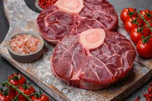 Frais brut du boeuf steak avec OS ou Osso Buco avec sel, épices et herbes photo