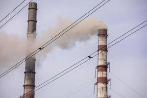 fumée de deux cheminées industrielles, tuyaux, contre le ciel. réchauffement climatique. la pollution de l'air. pollution écologique. émissions atmosphériques qui polluent la ville. les déchets industriels sont dangereux pour la santé. photo