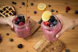 en buvant en bonne santé baie smoothies - myrtille, la mûre et framboise - femme mains photo