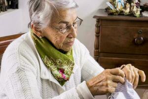 Sénior femme couture une fait maison visage masque pendant le convoitise 19 pandémie photo