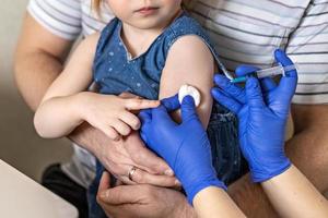 une petite fille avec son père dans le cabinet du médecin de la clinique se fait vacciner contre le coronavirus.le concept de vaccination, immunisation, prévention contre covid-19.