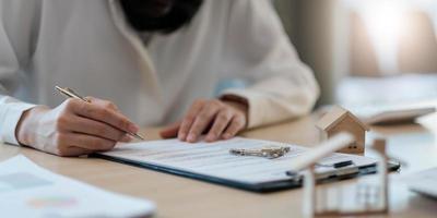 agent immobilier avec un modèle de maison mettant à la main le contrat de signature, avoir un contrat en place pour le protéger, signer des accords modestes au bureau. photo