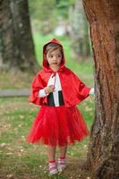 sucré fille portant une peu rouge équitation capuche costume. réel famille ayant amusement tandis que en utilisant costumes de le peu rouge équitation capuche conte dans Halloween. photo