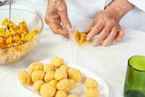 préparation de le traditionnel galettes de le Région de Cauca dans Colombie, appelé Empanadas de pipien - Sénior femme remplissage le galettes photo