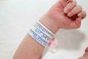 fermer de une nouveau née bras et bracelet à hôpital sur le journée de sa naissance photo