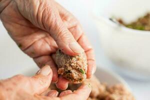 étape par étape levantin cuisine kibbeh préparation. proche en haut de une Sénior femme mains façonner une kibbeh photo