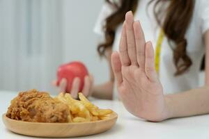 svelte corps femmes refuser vite nourriture ou déchet nourriture, femelle choisir Pomme pour régime. bien en bonne santé aliments. poids perdre, équilibre, contrôle, réduire graisse, faible calories, routines, exercer. rejet symbole photo