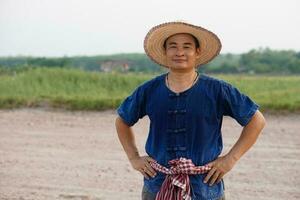 Beau asiatique homme agriculteur porte chapeau, bleu chemise, mettre main sur taille. ressentir confiant. concept , agriculture profession. thaïlandais agriculteur . photo