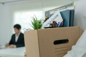 les hommes d'affaires stressants démissionneront de l'entreprise. il soulève une boîte en papier brun contenant des objets personnels. concept de démission, de placement et de postes vacants. photo