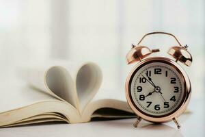 cloche alarme l'horloge et ouvert livre avec cœur en forme de page photo