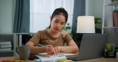 jeune asiatique femme travail avec une portable et l'écriture sur papier sur une bureau photo