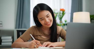 jeune asiatique femme travail avec une portable et l'écriture sur papier sur une bureau photo