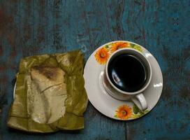 farci tamale avec tasse de café servi sur en bois tableau, traditionnel farci piqué tamal suivant à tasse de café servi sur en bois tableau, central américain typique nourriture farci tamal piqué photo