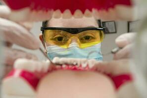 une dentiste nettoyage une bouche à l'intérieur voir, à l'intérieur vue de une bouche vérifié par une dentiste, une femelle dentiste vérification une patient. dentiste vérification une bouche, une dentiste nettoyage dents. photo