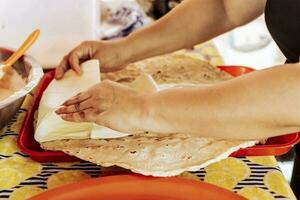 mains en train de préparer le traditionnel nicaraguayen quesillo, préparation de traditionnel nicaraguayen quesillo. la personne fabrication délicieux nicaraguayen fromage. traditionnel fromage avec mariné oignon. photo