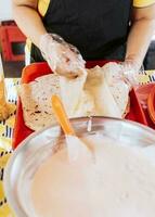 fait maison nicaraguayen quesillo, traditionnel central américain nourriture quesillo. mains fabrication une nicaraguayen quesillo. proche en haut de mains fabrication une traditionnel quesillo avec mariné oignon. photo