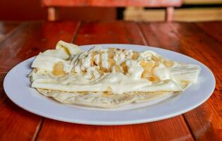 assiette de délicieux quesillo avec mariné oignon servi sur le tableau, traditionnel quesillo assiette avec mariné oignon et crème. concept de typique nicaraguayen nourriture photo