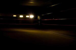 une vaguement allumé boxe bague dans une foncé chambre. ai généré photo