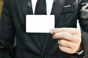 fermer de homme d'affaire qui prend en dehors blanc pièce de papier de le poche dans noir costume. idée pour affaires crédit carte ou visite carte. photo