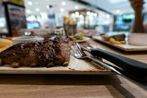 vue partielle en gros plan d'une femme qui aime manger du steak avec une fourchette et un couteau au restaurant photo