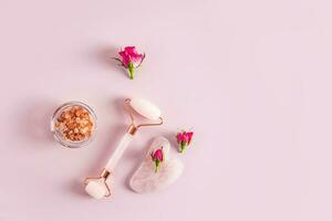 Rose quartz masseur, gua sha grattoir, sel dans une bol et petit boutons de rose. Haut voir. rose Contexte. une copie espace. Naturel se soucier. photo