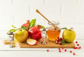 de fête encore la vie pour rosh hashanah. une ensemble de traditionnel nourriture Miel, Grenade, pommes sur une en bois planche. le concept de le juif Nouveau an. photo