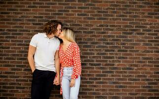 souriant Jeune couple dans l'amour dans de face de maison brique mur photo