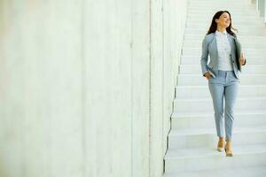 Jeune affaires femme en marchant vers le bas le escaliers et en portant portable photo