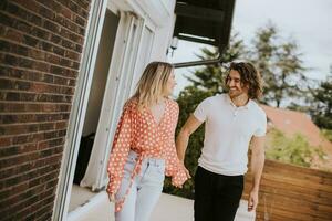 souriant Jeune couple dans l'amour en marchant dans de face de maison brique mur photo