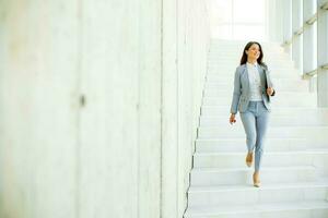 Jeune affaires femme en marchant vers le bas le escaliers et en portant portable photo