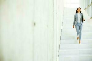 Jeune affaires femme en marchant vers le bas le escaliers et en portant portable photo