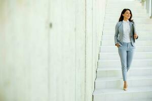 Jeune affaires femme en marchant vers le bas le escaliers et en portant portable photo