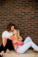 souriant Jeune couple dans l'amour dans de face de maison brique mur photo