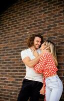 souriant Jeune couple dans l'amour dans de face de maison brique mur photo