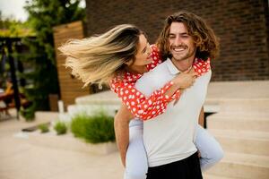 Beau longue cheveux homme porter le Jeune femme sur le sien retour dans de face de brique maison photo