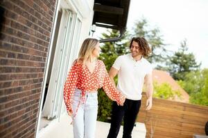 souriant Jeune couple dans l'amour en marchant dans de face de maison brique mur photo