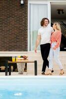 Jeune couple relaxant par le nager bassin dans le maison arrière-cour photo