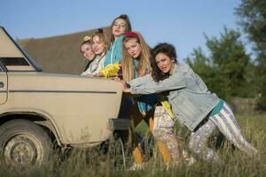 Jeune de bonne humeur les filles sont pousser un vieux auto. femmes dans le style de le années 90. photo