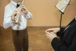 une la musique prof écoute à une étudiant en jouant le flûte dans une la musique école. photo