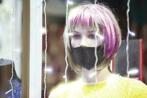 femme mannequin avec triste yeux dans une médical masque dans une magasin la fenêtre. photo