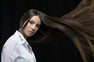 magnifique brunette avec longue en volant cheveux sur une foncé Contexte. photo