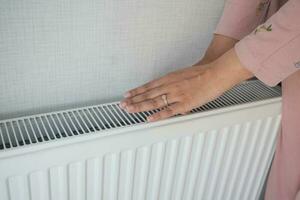 femme chauffage mains près électrique chauffe-eau à maison. photo