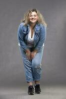 magnifique dodu femme dans une denim costume sur une gris Contexte. photo