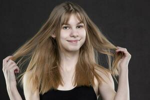 une magnifique adolescent fille desserré sa cheveux regards et sourit. photo