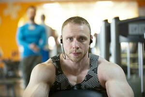 une Beau Jeune fort homme de un athlétique physique est engagé sur une des sports simulateur. photo