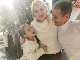 famille, vacances, La technologie et gens - souriant mère, père et peu fille fabrication selfie avec caméra plus de vivant pièce et Noël arbre Contexte photo